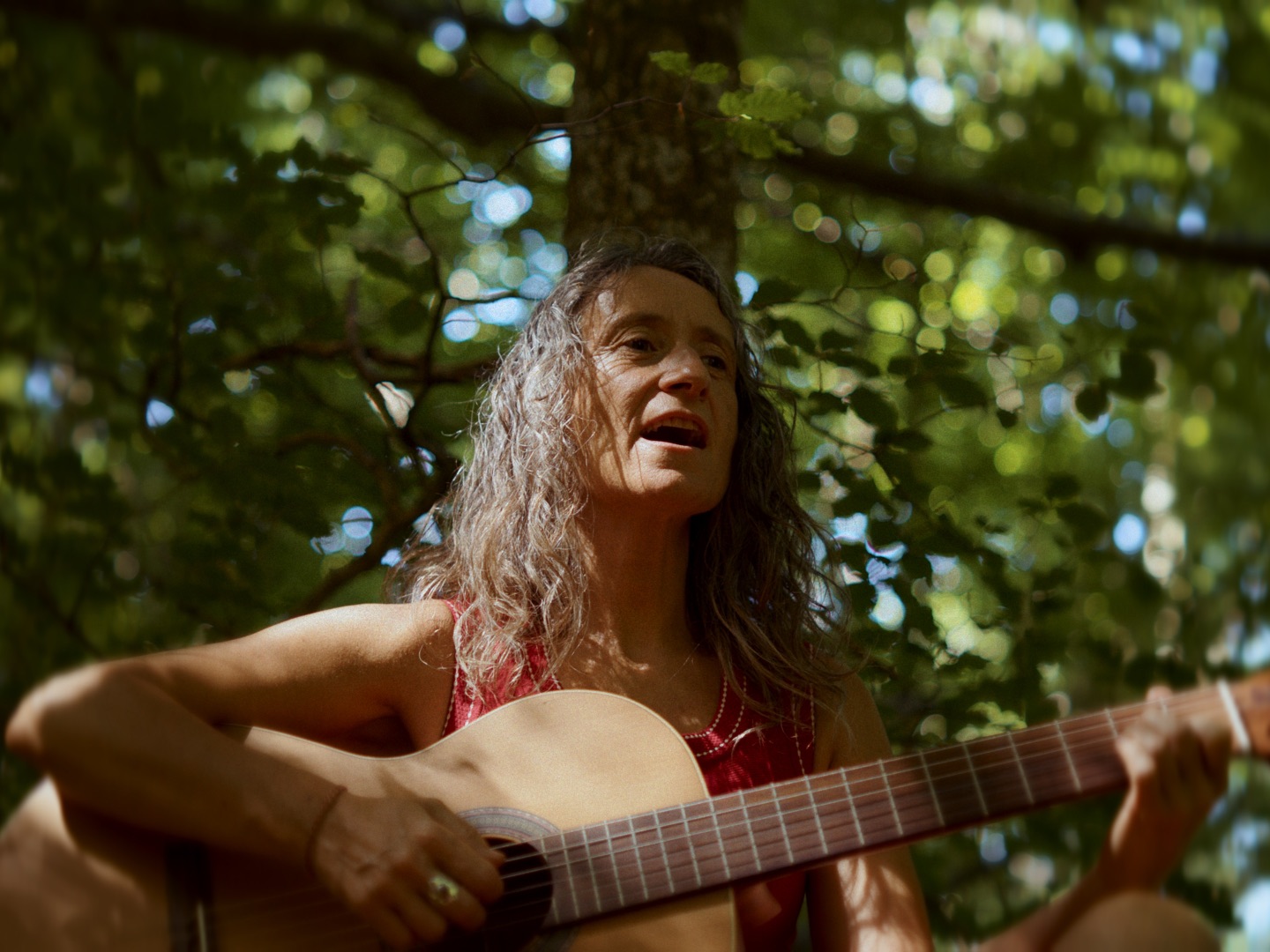 Txari cantando con la guitarra junto a un árbol
